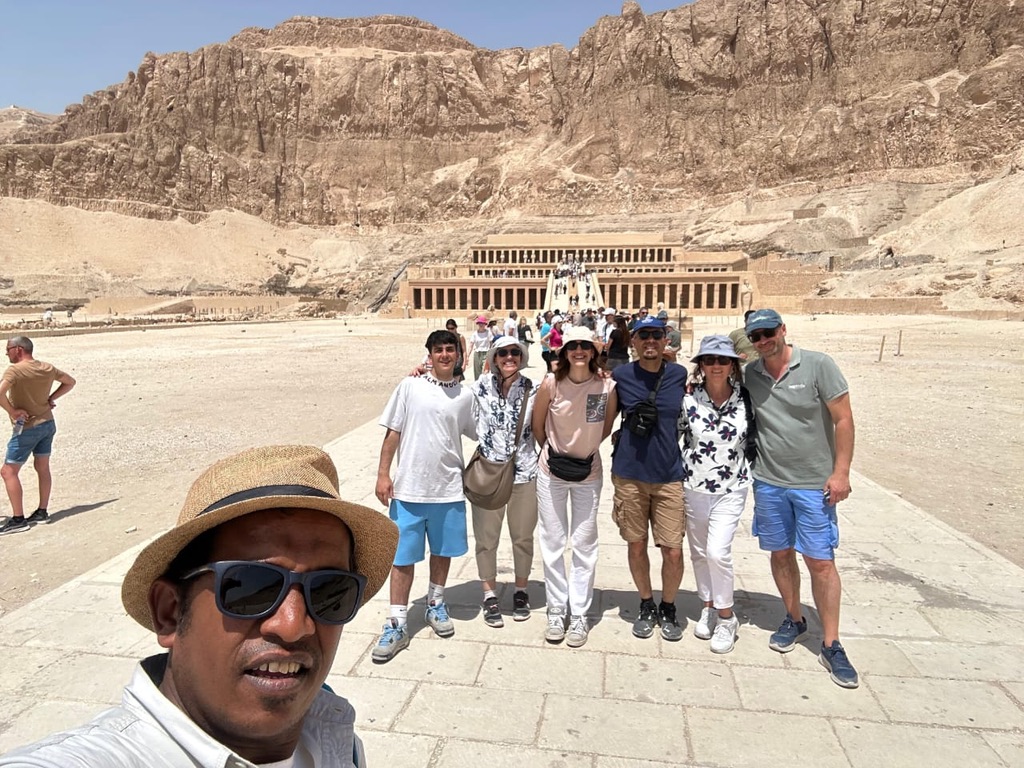 Mostafa with international group at Hatshepsut Temple cliffs - breathtaking desert landscape